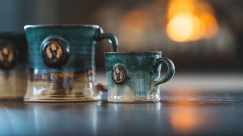 Deer Valley ceramic mugs infront of fireplace.