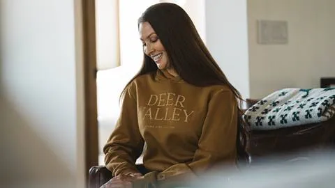 Woman wearing Deer Valley sweatshirt inside a lodging property.