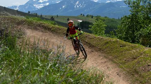 Boy wearing a red t-shirt is mountain biking at Deer Valley.