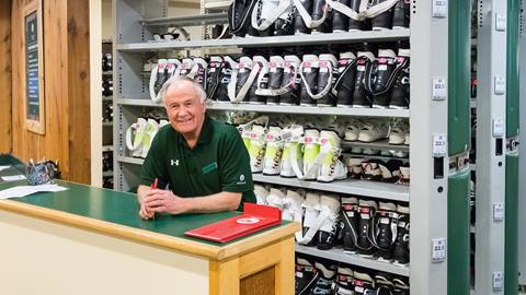 Deer Valley ski rental technician smiling by table.