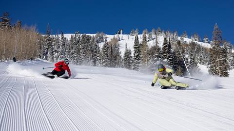 Ted Ligety and Kaylin Richardson skiing a groomed run together.