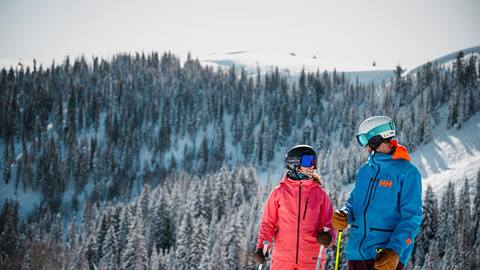 Couple smiling while standing on ski run at Deer Valley.