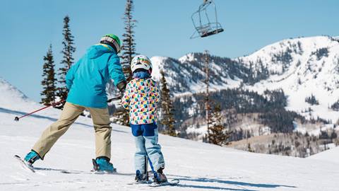 Father and young girl daughter skiing together.