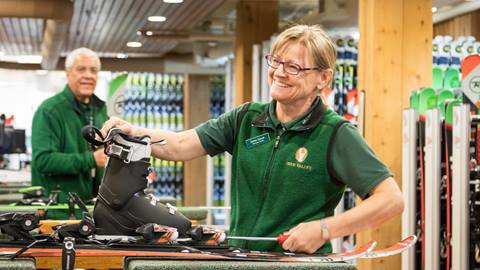 Female ski rental technician fitting ski boots.