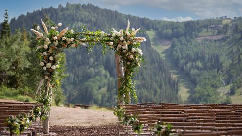 Outdoor wedding ceremony featuring flower arch at Deer Valley in the summer.